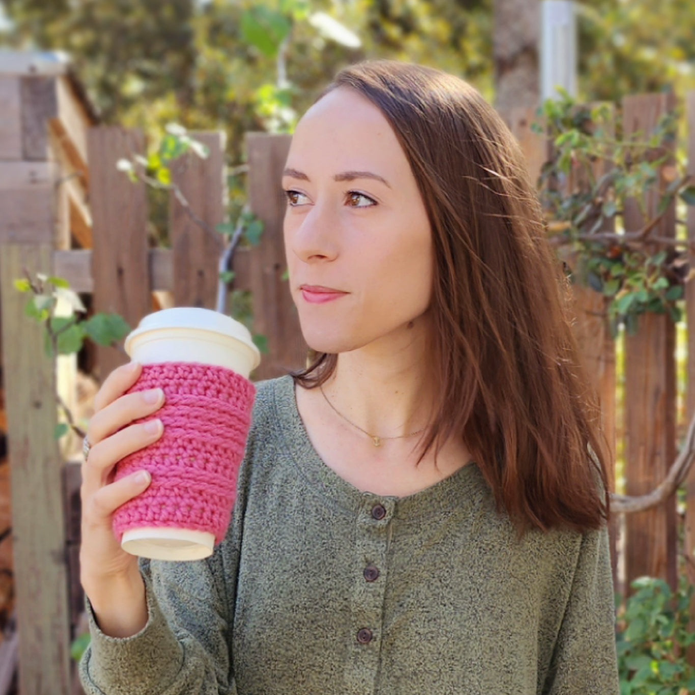 Rachel holding a coffee and looking into the distance.