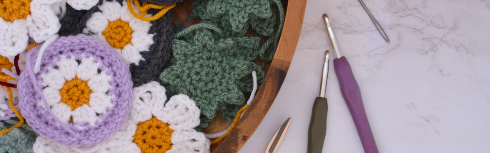 Crocheting scene with a collection of handmade car coasters. Coasters are granny flowers and succulent shaped.