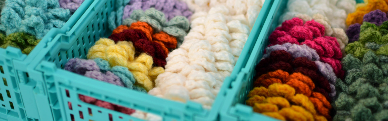 Crochet car coasters shown organized in small turquoise crates.