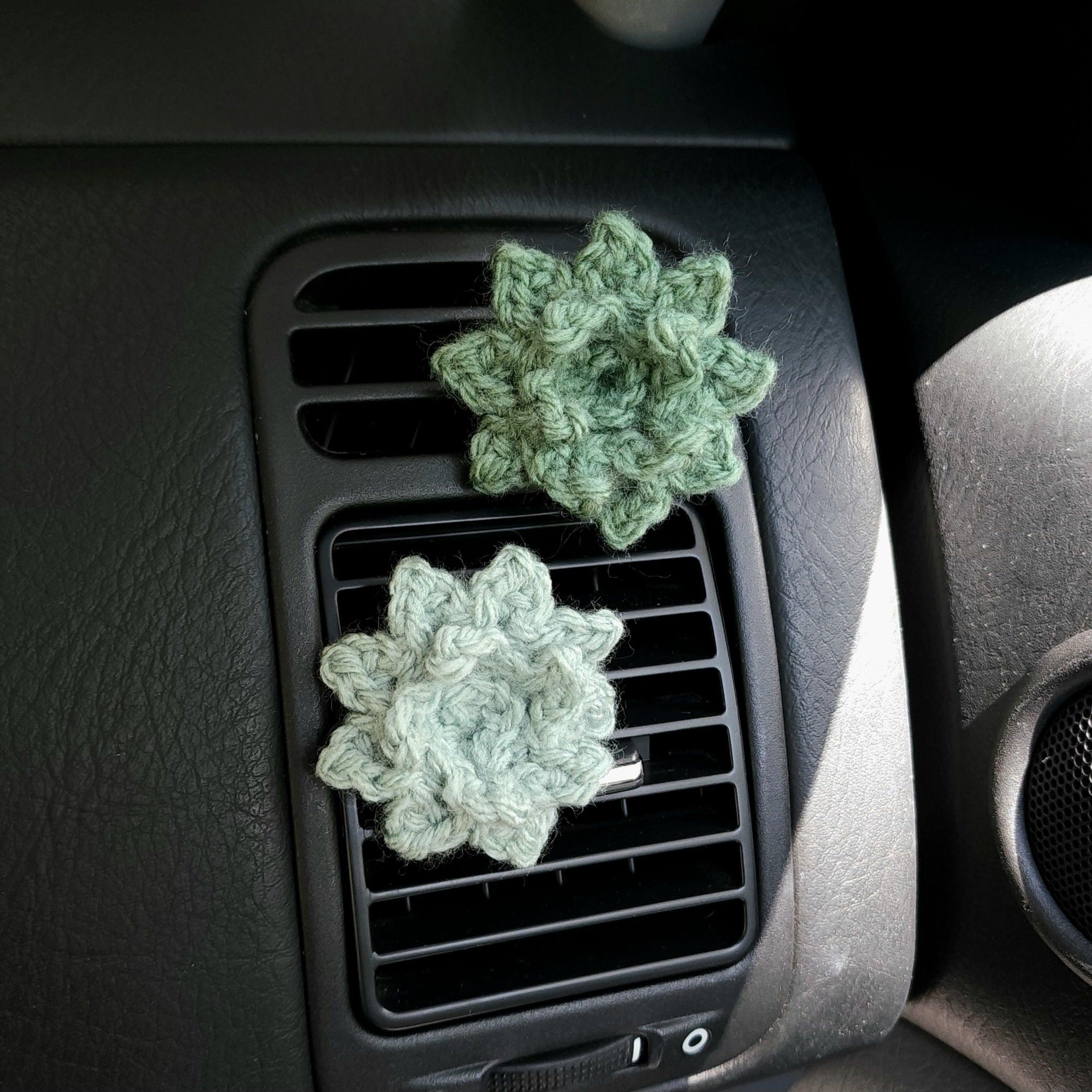 Set of two succulent shaped accessories shown on car interior air vents.